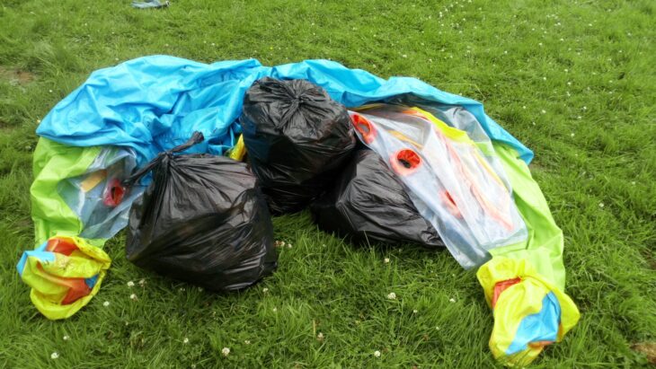 pile of bin bags with deflated children's paddling pool placed on grass